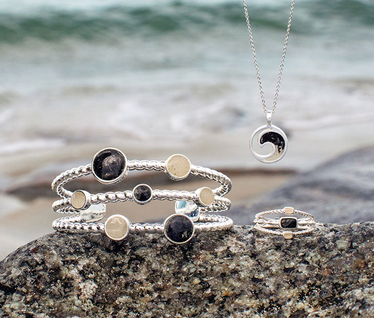 Dune Florida collection: necklace, bracelet, and ring on a rock at the beach