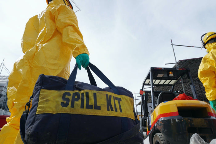 People in hazmat suits carrying a spill kit for an ocean cleanup.