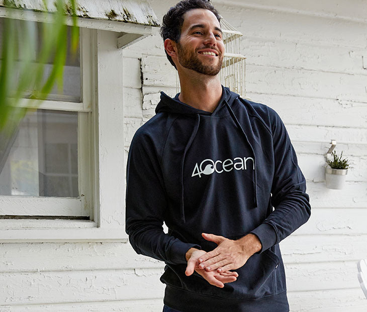 The 4ocean long sleeve hoodie in black. The hoodie is on a male model and has the 4ocean logo on the front in white.