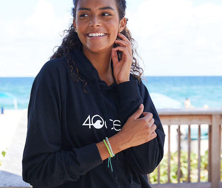 The 4ocean long sleeve hoodie in black. The hoodie is on a female model and has the 4ocean logo on the front in white.