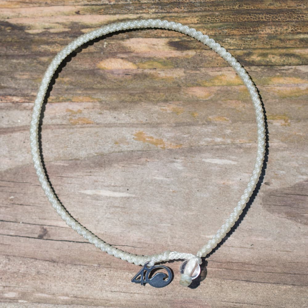 4ocean Polar Bear Braided Bracelet with a wood background