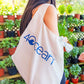 4ocean x ChicoBag Reusable Shopping Bag - white on the shoulder of a model.