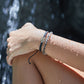 A female modeling our crew bracelet and shark beaded bracelet with the waterfall in the background 