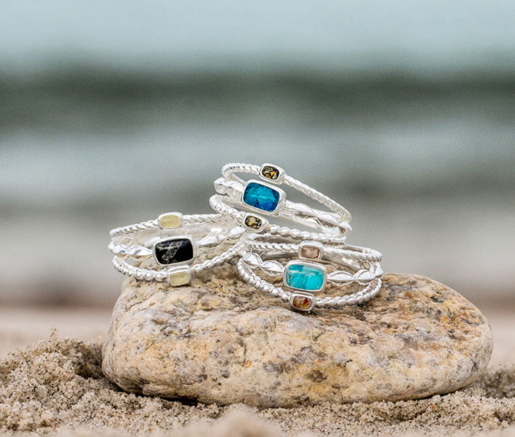 Dune Florida Ring, Dune Bali Ring, and Dune Hawai'i Ring stacked on a rock on the beach