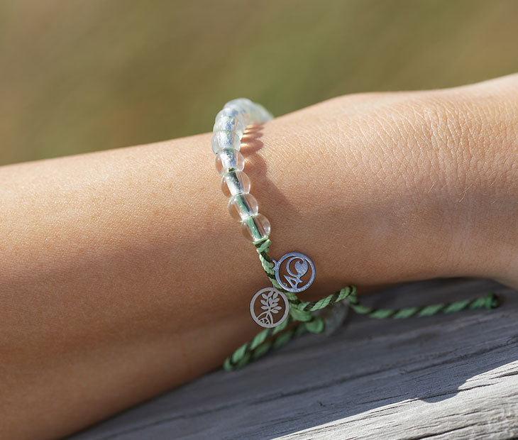 4ocean Earth Day Beaded Bracelet 2022 - green. On wrist of female model.
