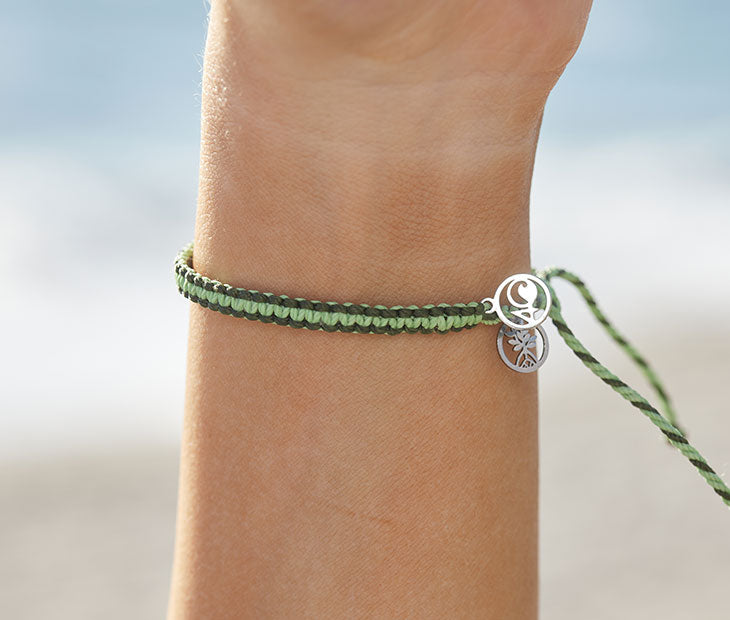 4ocean Earth Day Braided Bracelet 2022 - green. On wrist of female model.
