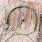 4ocean Earth Day Braided Bracelet 2022 - green. On drift wood.