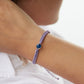 4ocean Purple Ocean Drop Bracelet. Purple braided cord with stainless and blue bezel. Shown on female model.