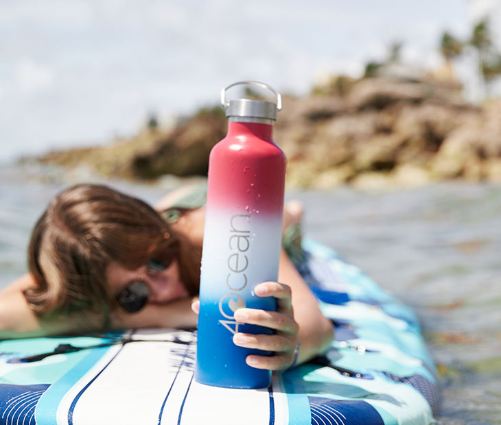 Large Reusable Bottle - Patriotic Ombre. Female surfer holding the bottle.