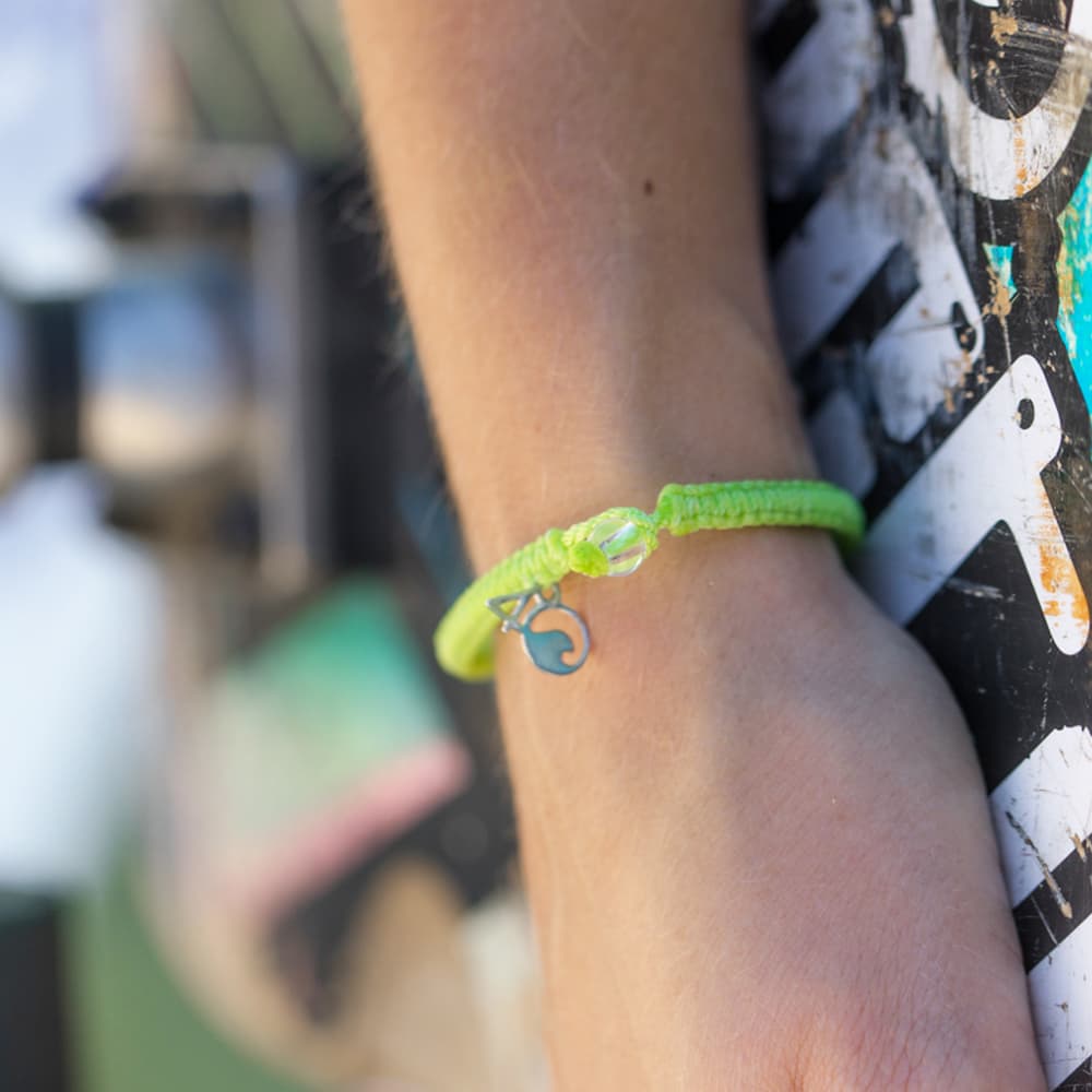 4ocean Sea Turtle Braided Bracelet on a wrist holding a skateboard