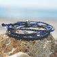 Shark Bracelet stack being displayed to showcase that 3 braided bracelets in our signature blue and black colors can be worn together as one or individually on a piece of driftwood