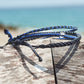 Shark Bracelet Stack being displayed on driftwood with the beach in the background
