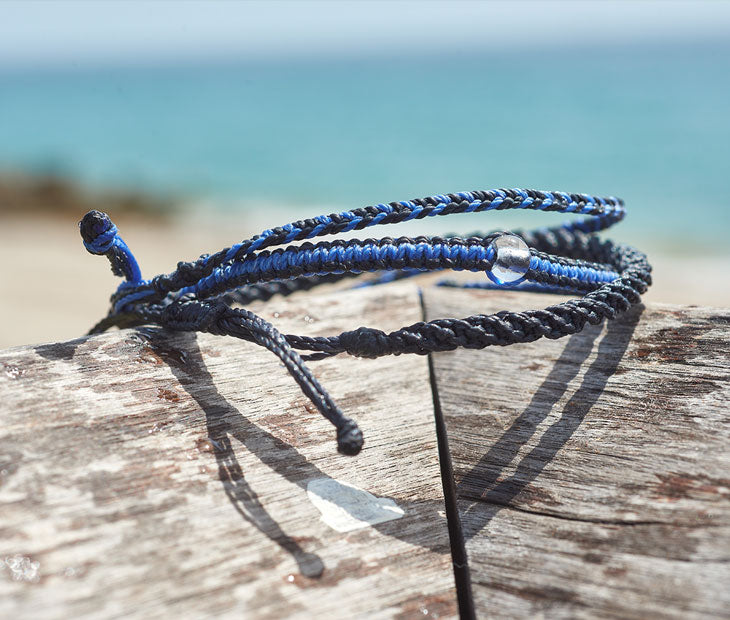 Shark Bracelet Stack being displayed on driftwood with the beach in the background