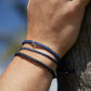 Shark Bracelet stack being modeled on a males hand with their arm against a piece of wood