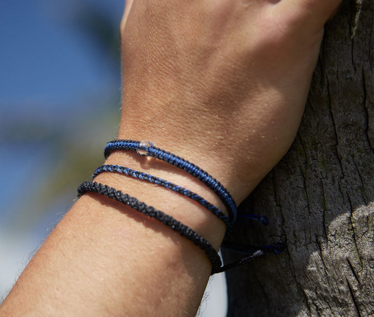 Shark Bracelet stack being modeled on a males hand with their arm against a piece of wood