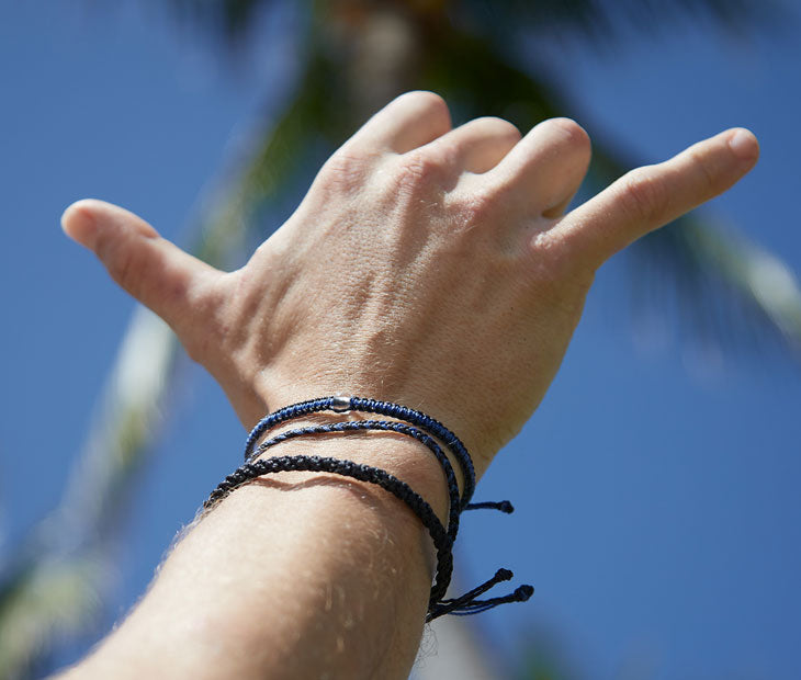 Shark bracelet stack being displayed by a male model making the shaka hand gesture
