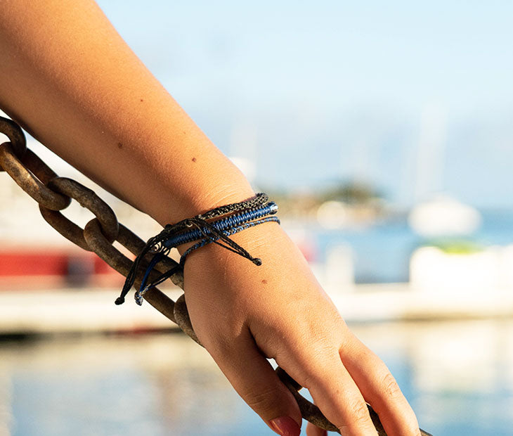 Shark Stack Bracelet being modeled on an females arm that's resting on a chain with the pier in the background 