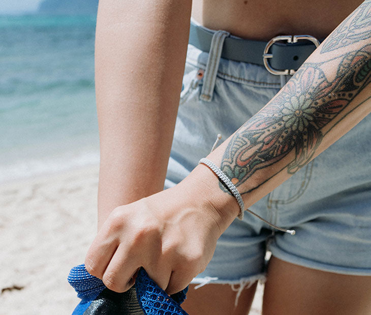 Tiger Shark braided bracelet being modeled on the beach by a female with artistic arm tattoos